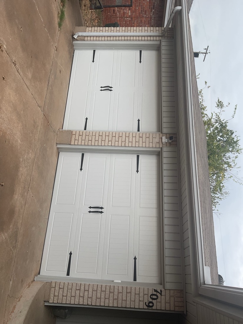 Two white garage door panels installed side-by-side on residential home.