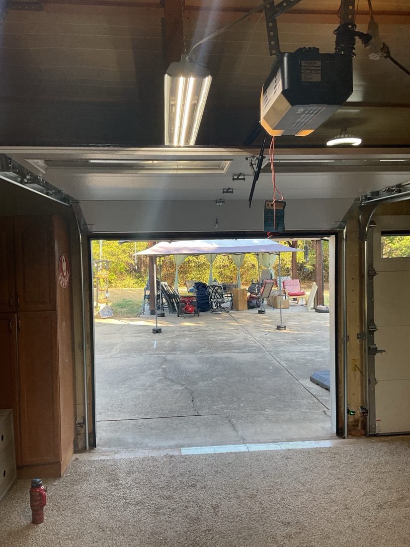 Wide-angle view of installed garage door opened showing openers and tracks.