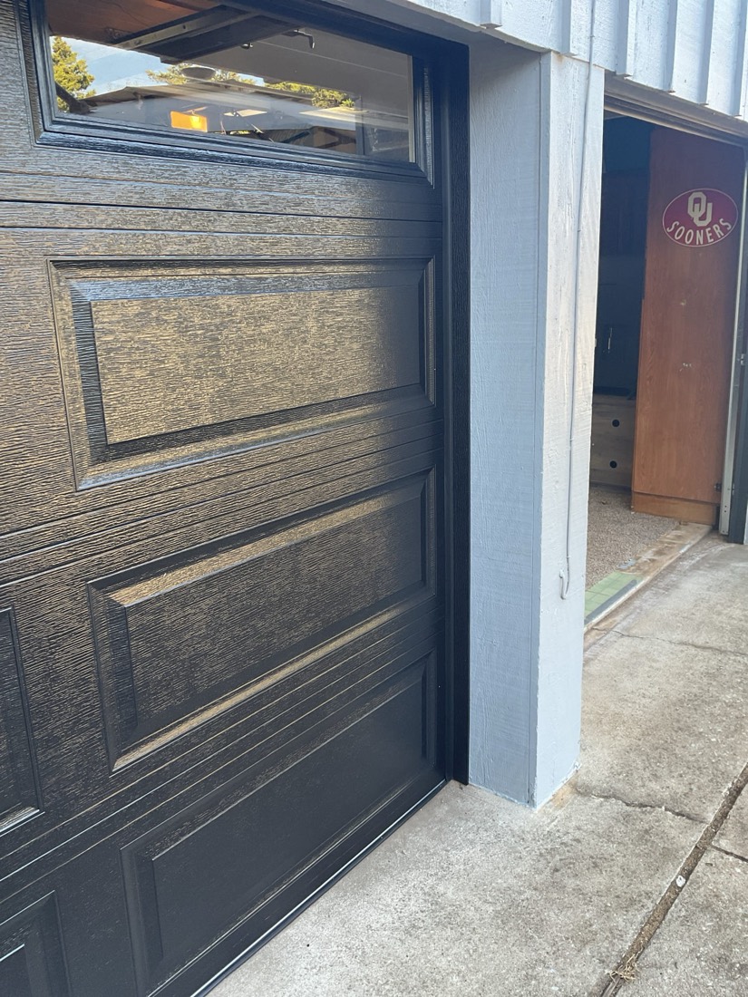 Installed black garage door with contemporary horizontal panel design.
