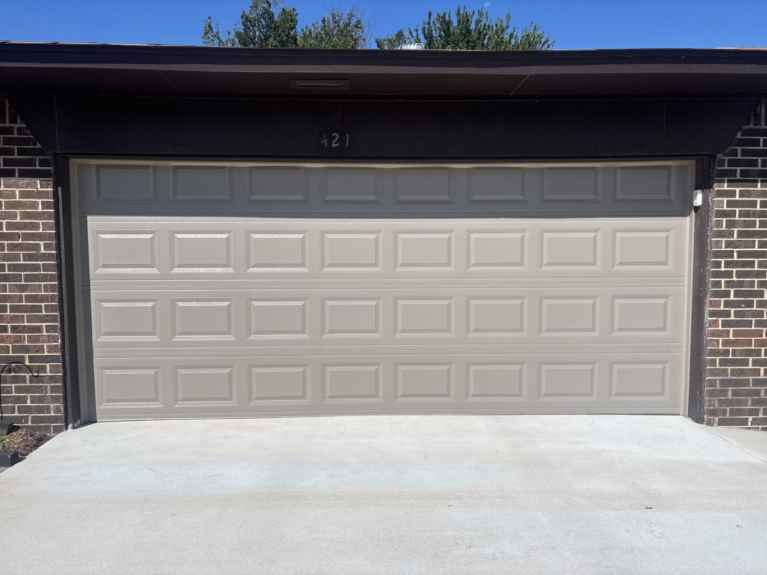 Cream-colored garage door installed on brick home exterior