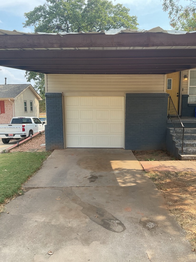 Cream garage door under pergola in residential driveway.
