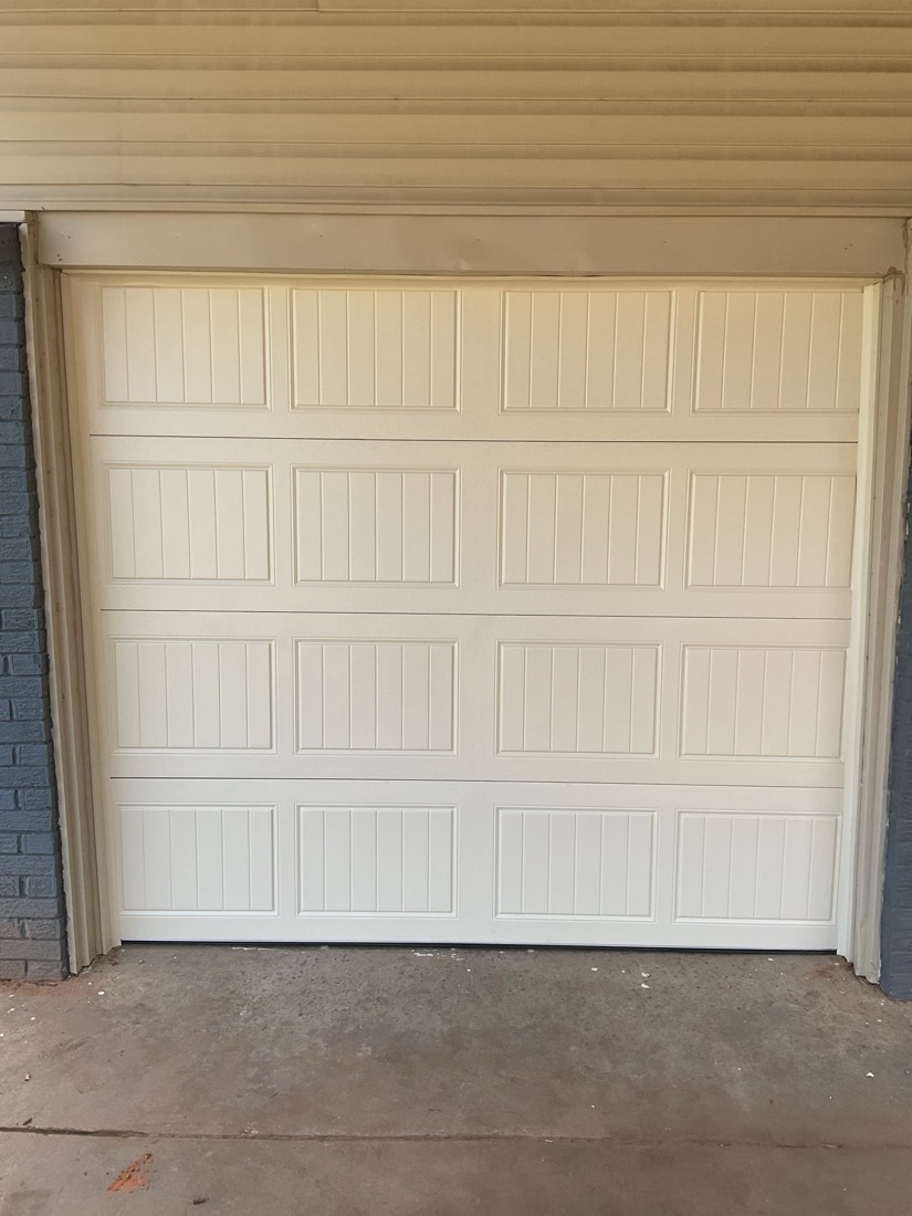 White vertical-panel garage door with new frame installation.