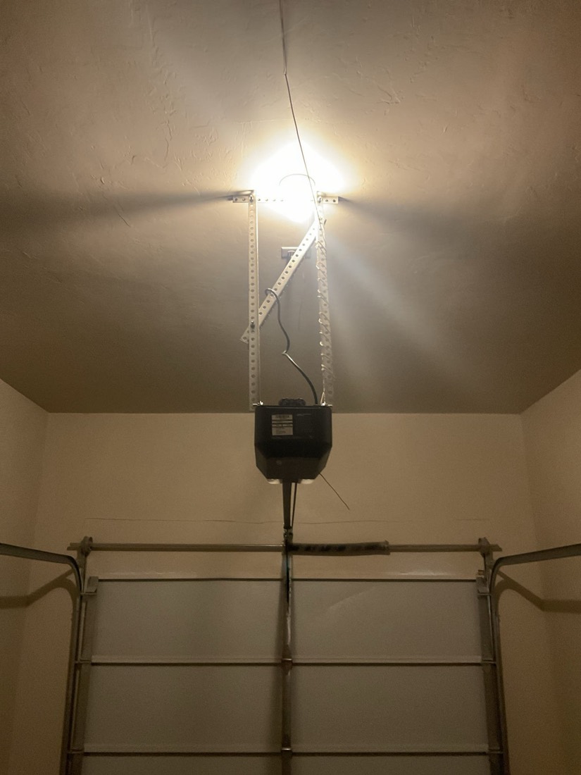 Garage door opener motor mounted to ceiling with steel track frame
