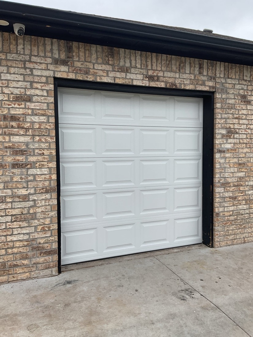 White six-panel garage door installed on brick home in Norman