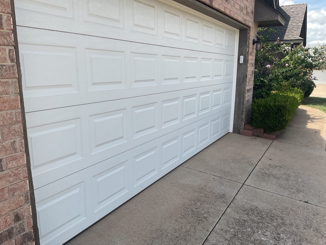Newly installed white garage door with clean appearance and driveway