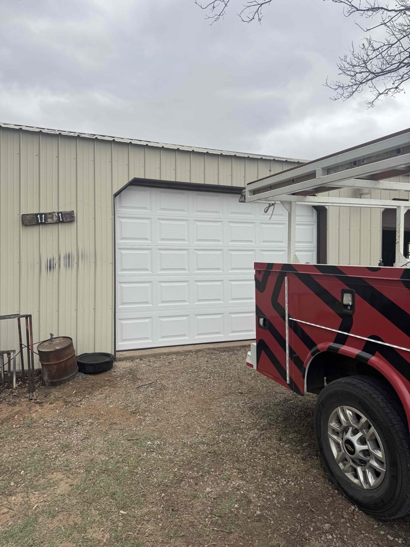 White raised-panel garage door installed on metal-frame building.