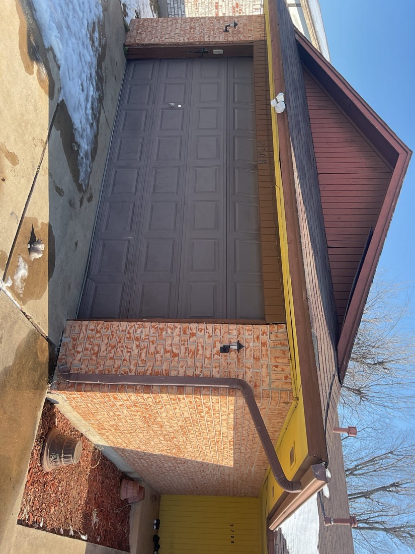 Completed dark brown garage door installation on brick house in Spencer, OK.