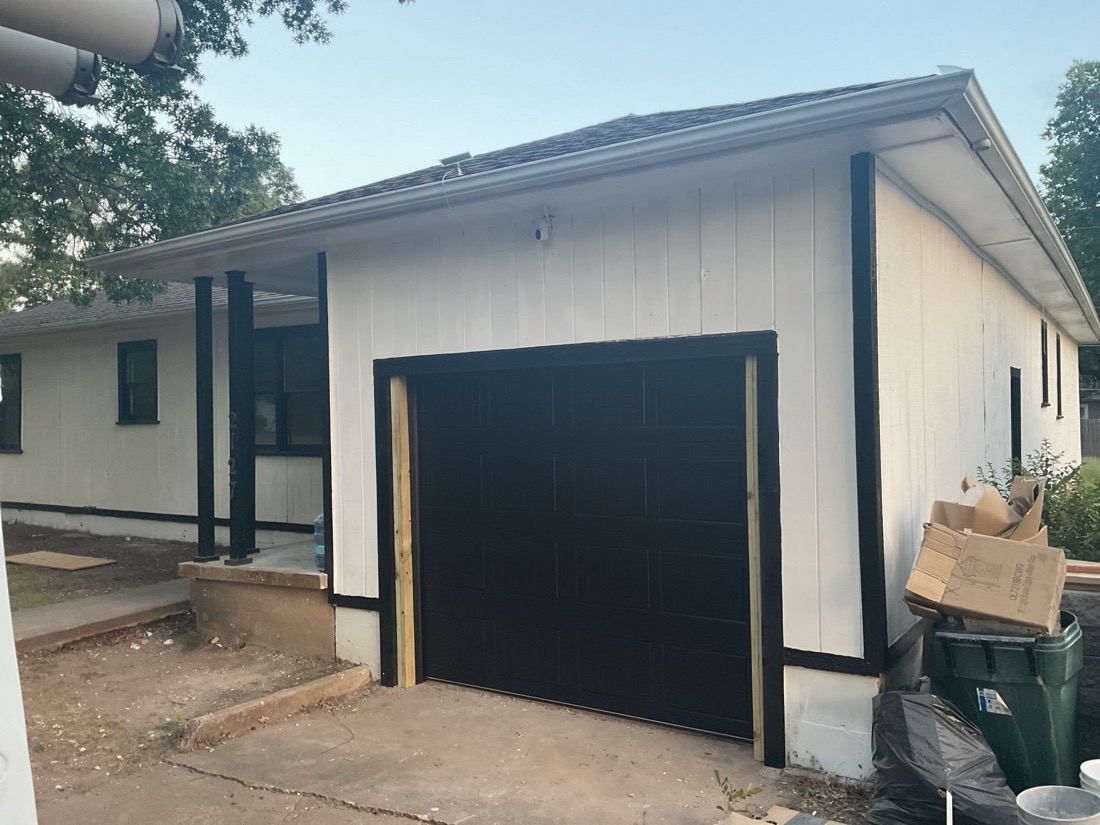 Installed black garage door with decorative hardware on home