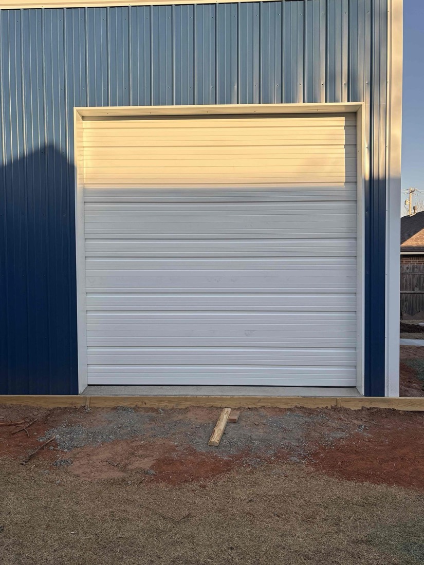 White garage door installed on blue metal building exterior