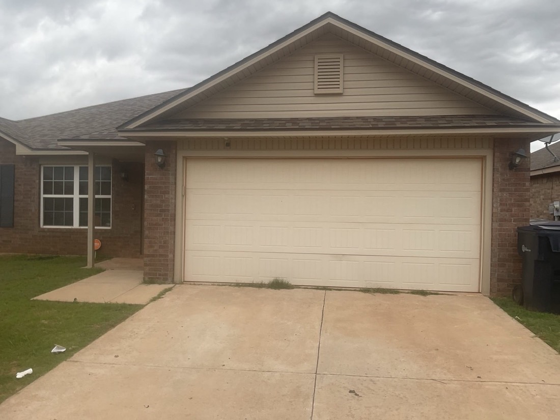 Finished white garage door installation on brick and siding home exterior
