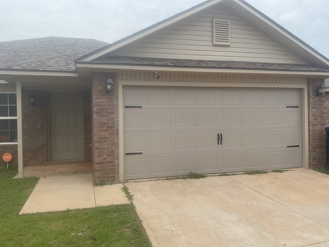 Newly installed white garage door with panel details on residential home