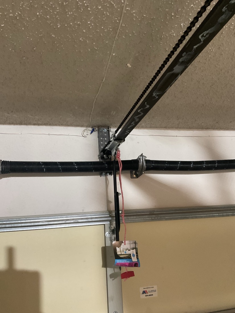 Metal garage door spring bracket and opener hardware assembly.