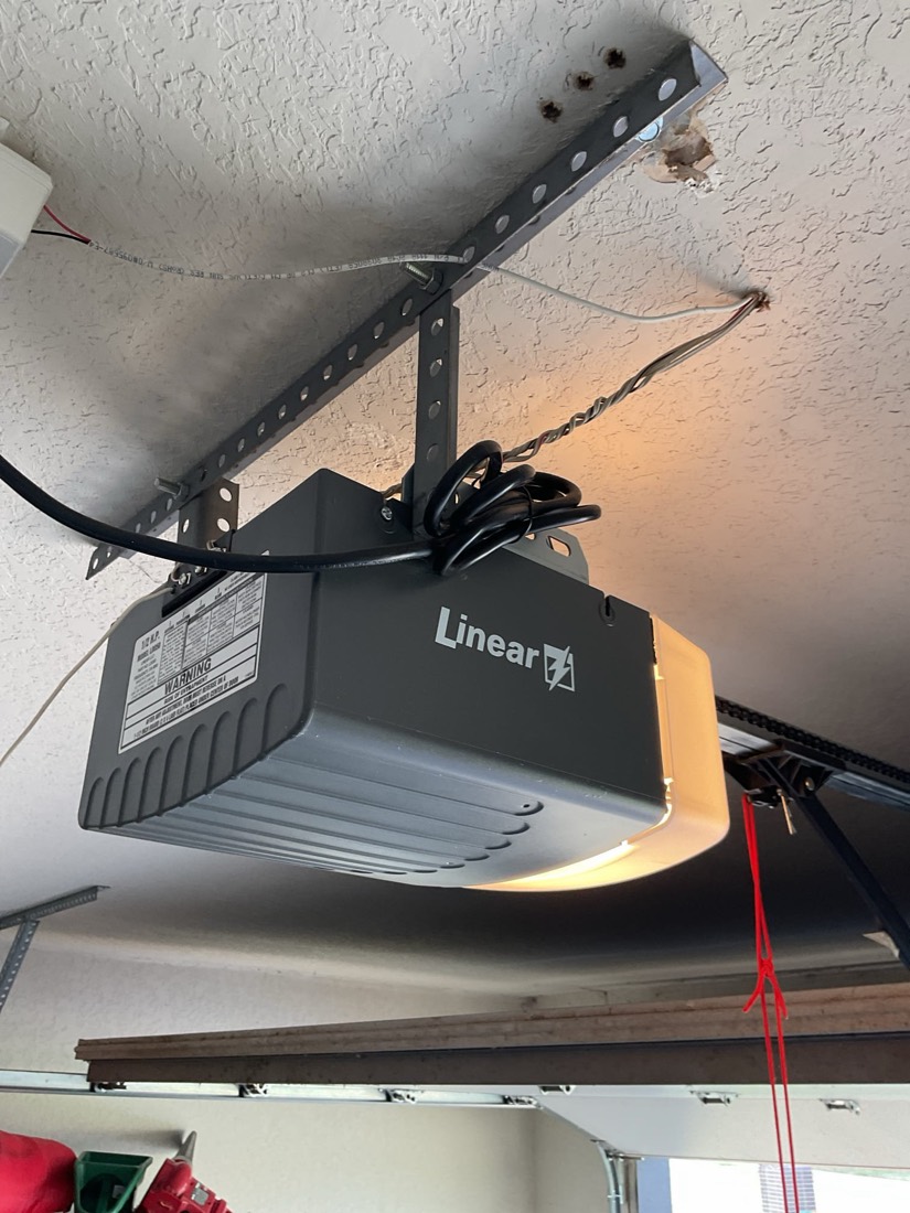 Linear garage door opener mounted to garage ceiling with mounting bracket
