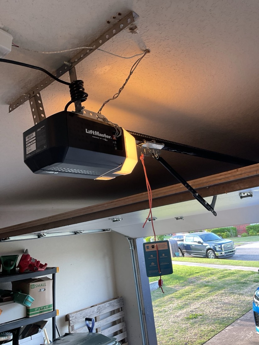 Liftmaster garage door opener mounted to garage ceiling with bracket and wiring
