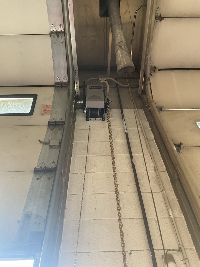 Installed garage door opener showing chain drive, motor, and hardware components