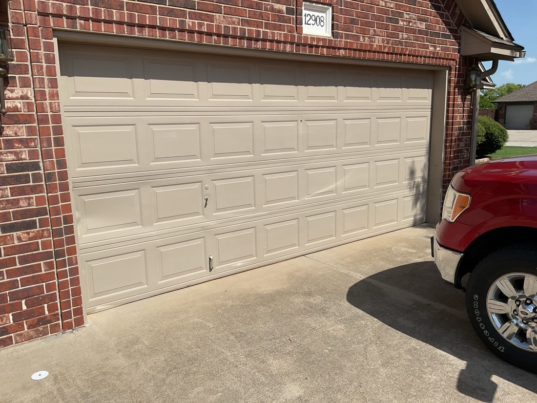 Two-panel beige garage door installed on residential brick home