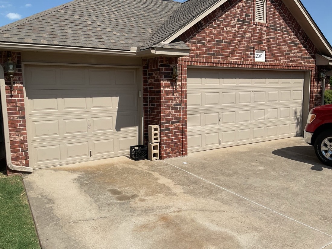 Newly installed two-panel beige garage door on brick home exterior