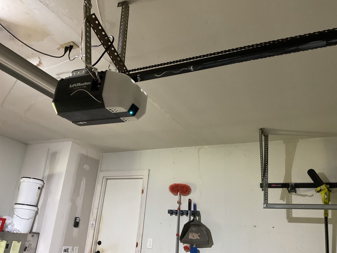 Installed garage door opener motor and rail assembly mounted to ceiling