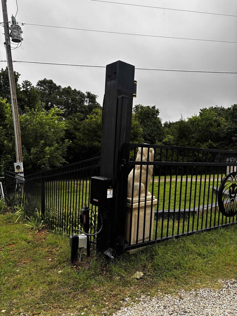 Black automated gate operator mounted on residential driveway entrance.