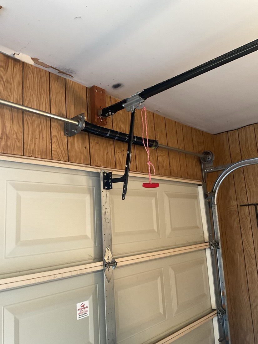 Newly installed black garage door spring and bracket on residential door