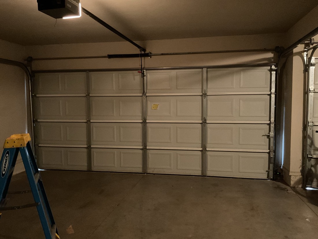 Completed garage door spring repair with new door panels and hardware installed