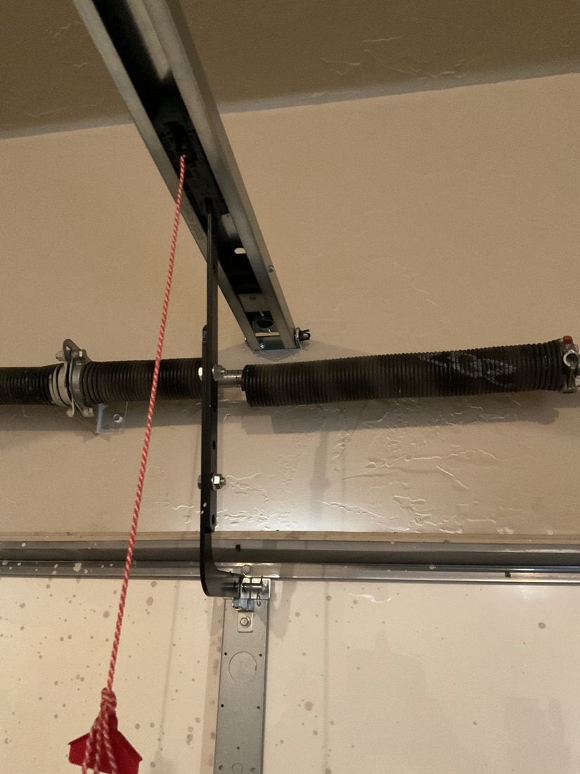 Installed garage door torsion springs with emergency cable and mounting hardware.