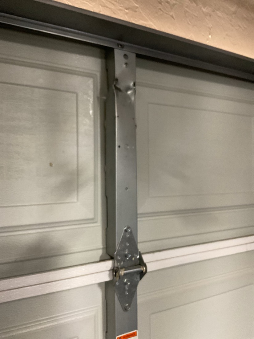 Metal bracket securing garage door panels.