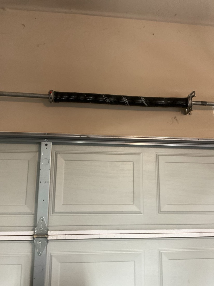 New torsion spring mounted on garage door shaft.