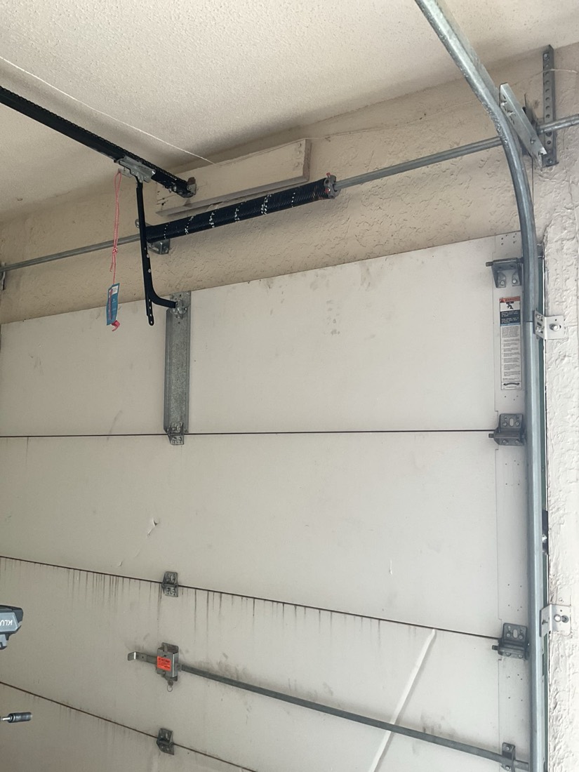 New black garage door spring bracket and tension system mounted on header.