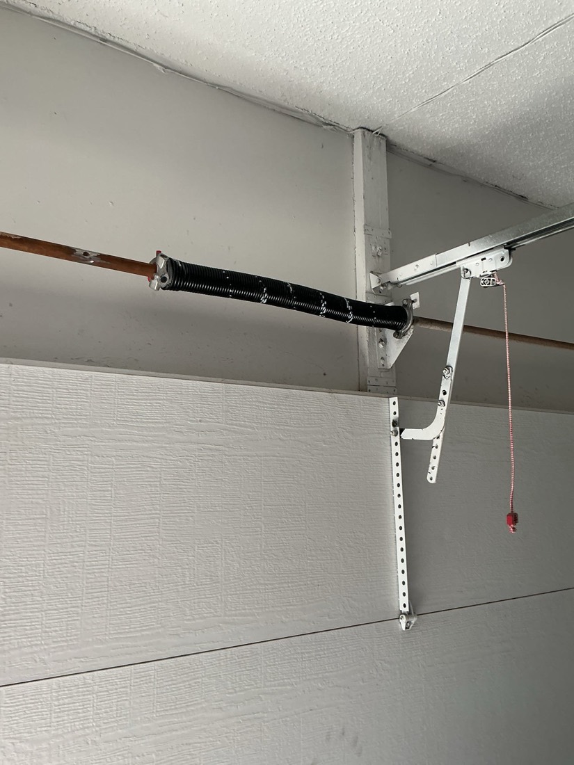 New torsion spring and mounting hardware on garage door assembly.