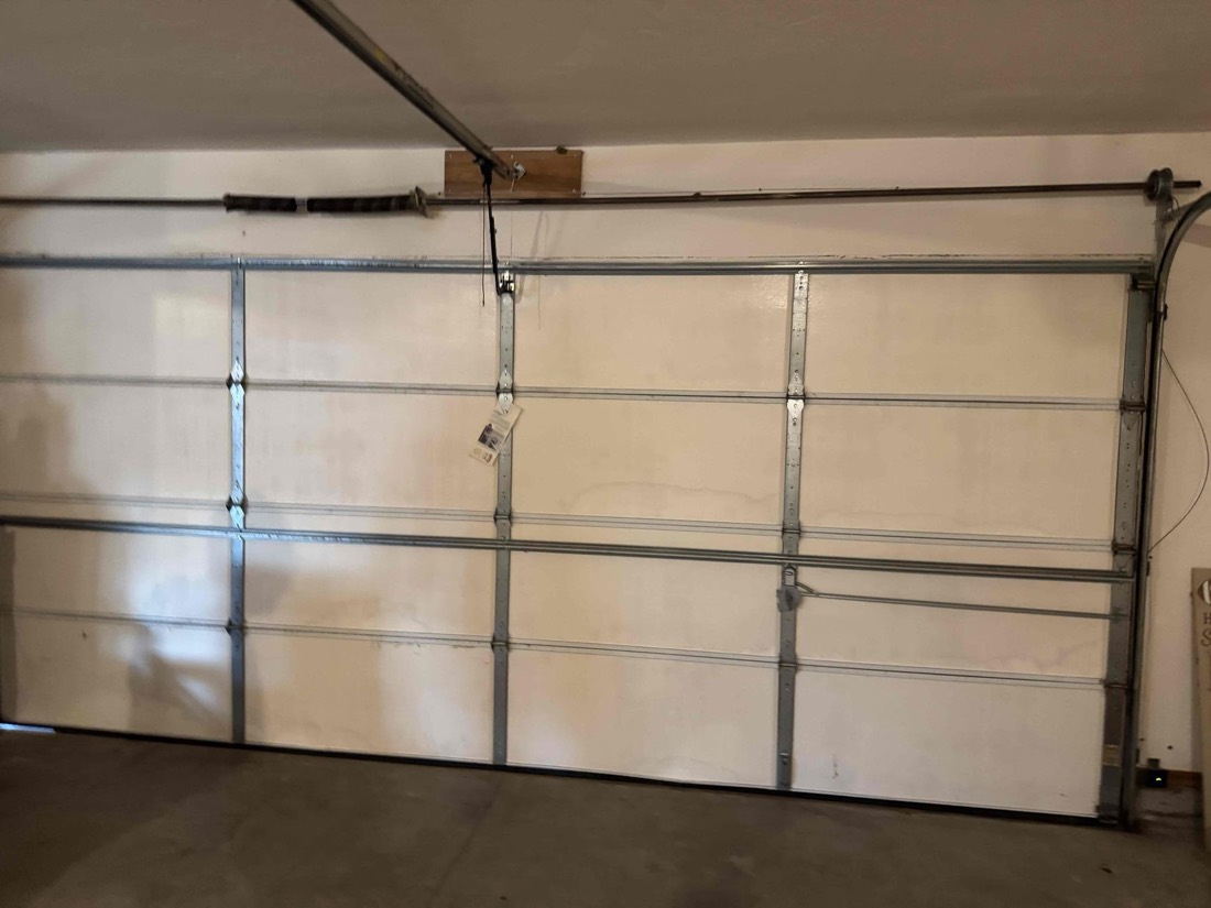 Interior view of garage door frame with tracks and spring mounting hardware.