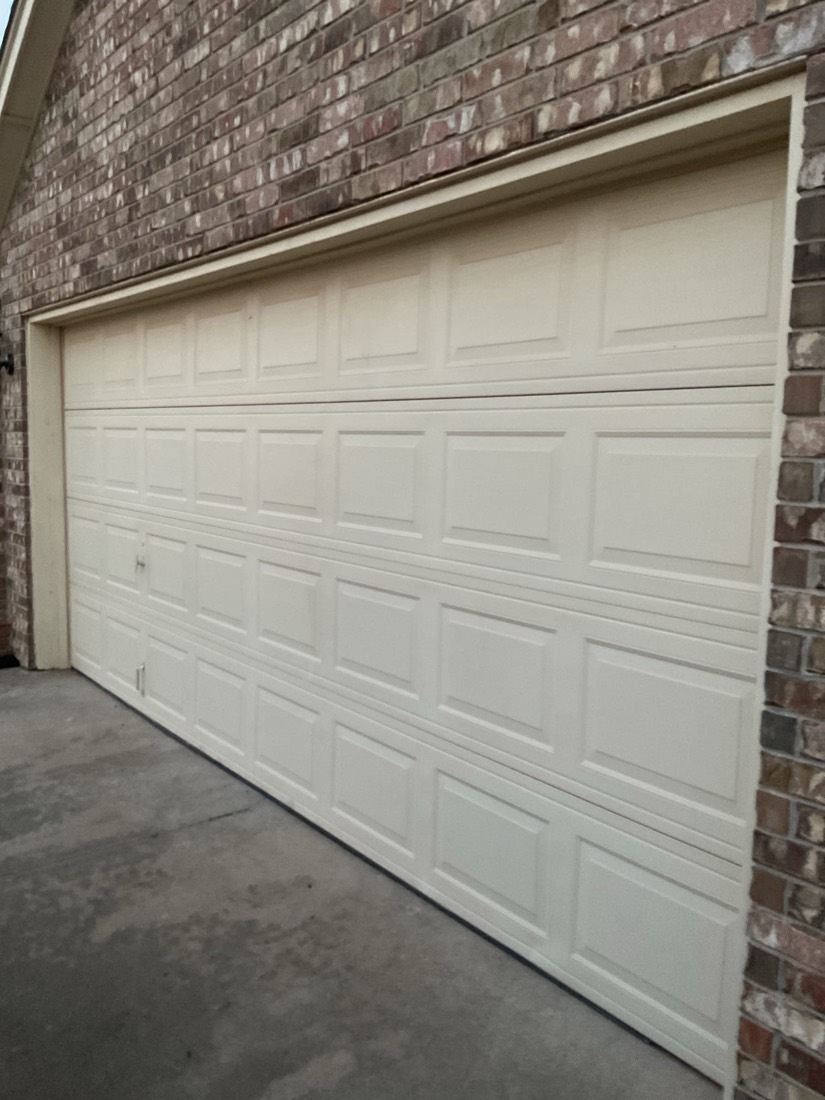 White multi-panel garage door on brick home exterior.