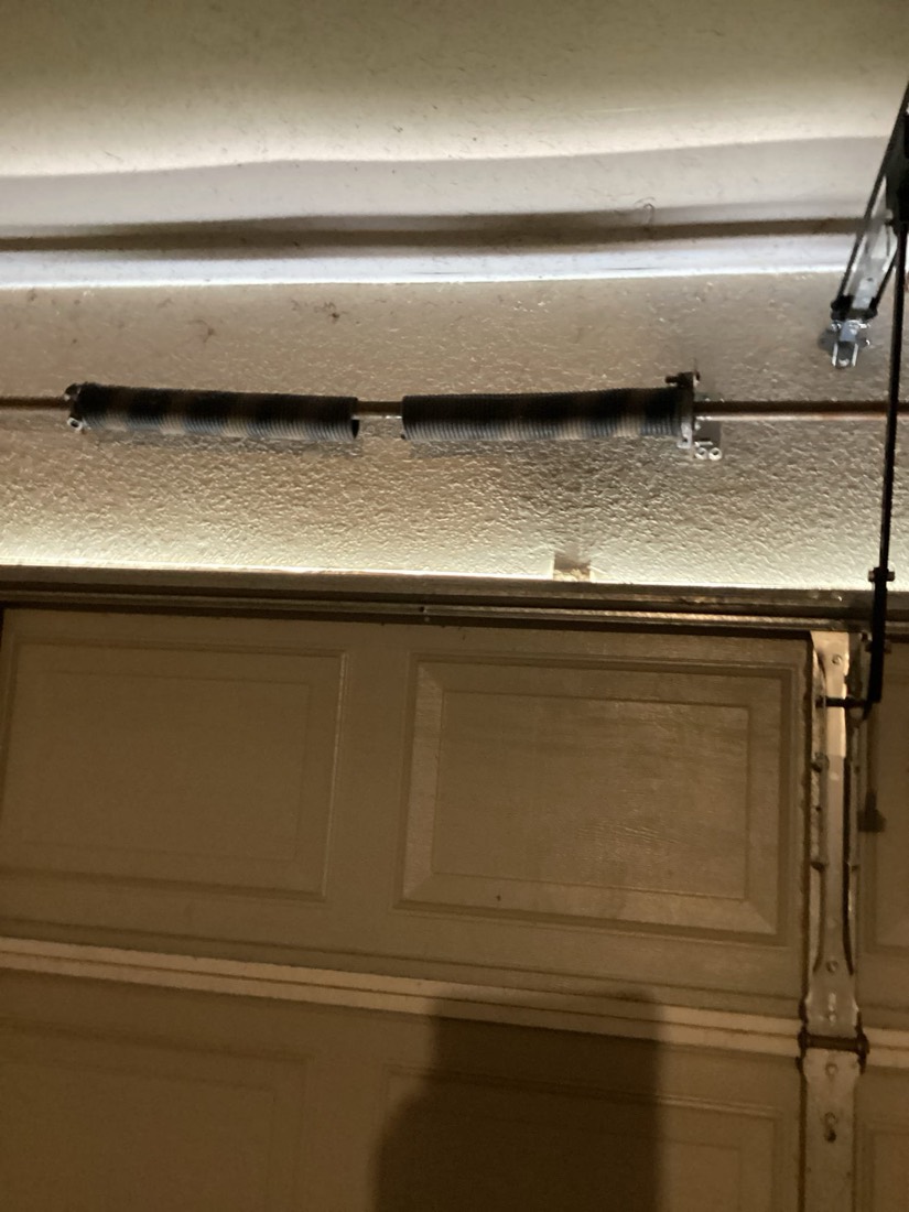 New garage door torsion spring mounted on bracket above door
