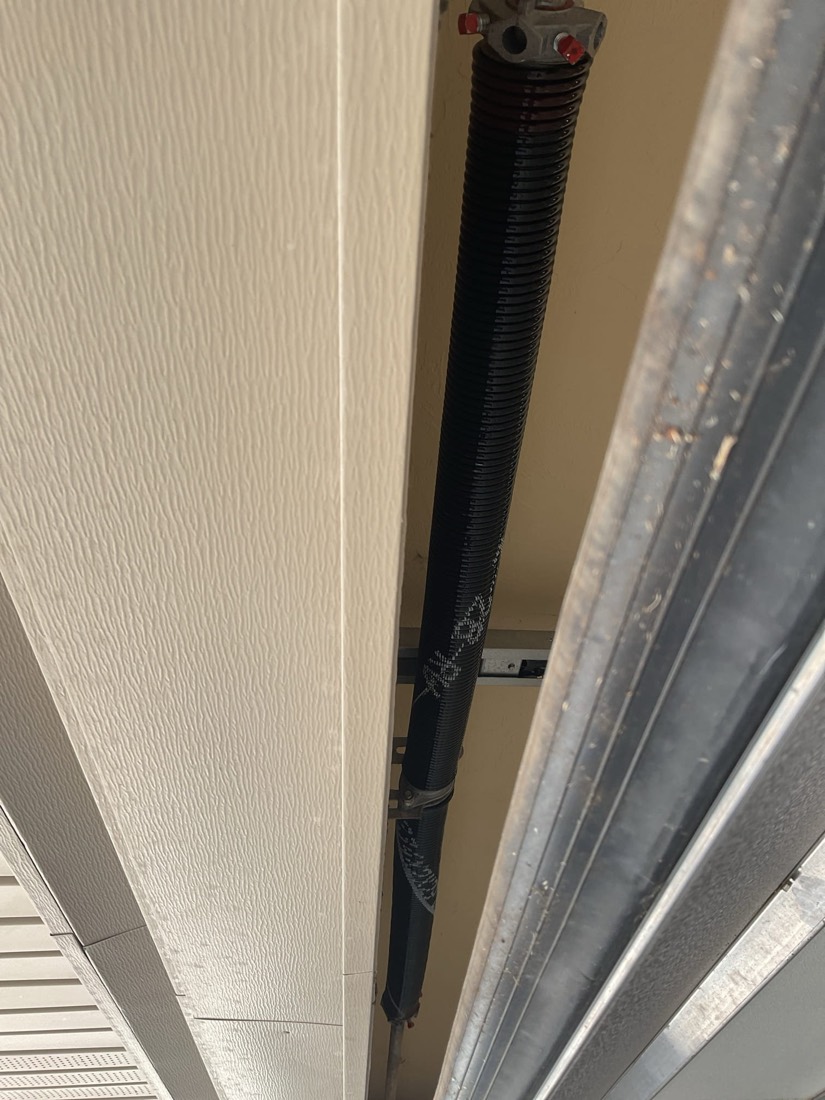 New black garage door spring installed on residential garage door.