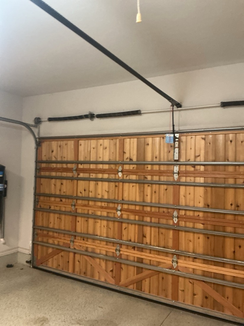 Interior view of wooden garage door with new springs and cable hardware