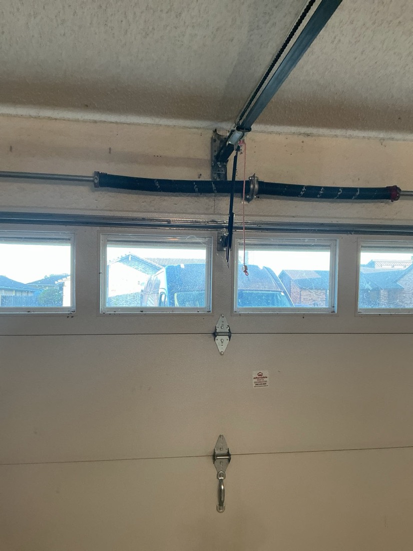 Installed garage door spring and mounting hardware on residential garage ceiling