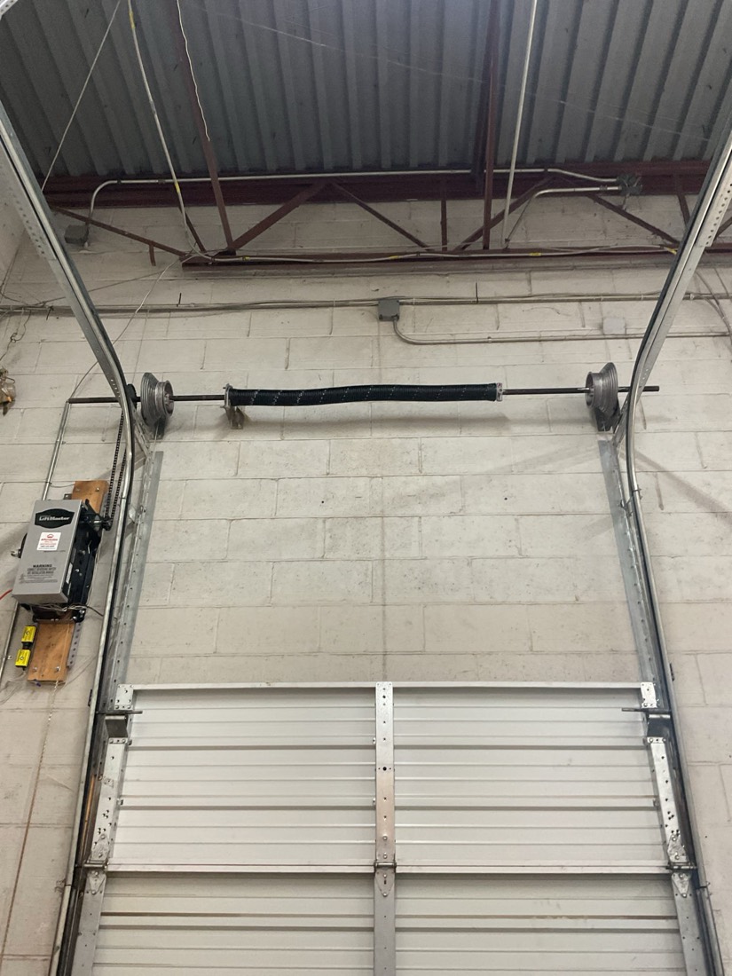 Garage door spring replacement showing new spring and pulley system installed.
