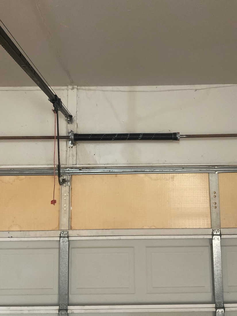 New black garage door spring mounted on the track system.