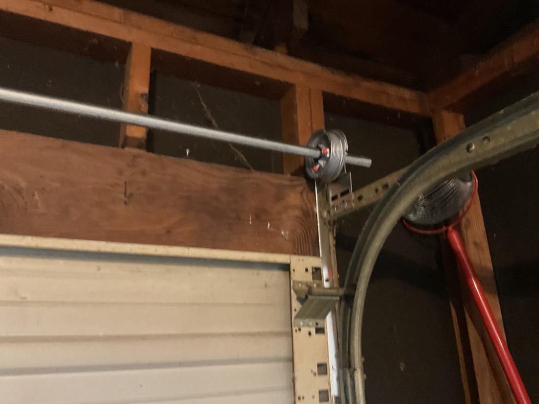 Newly installed garage door torsion spring and cable assembly with pulley system.