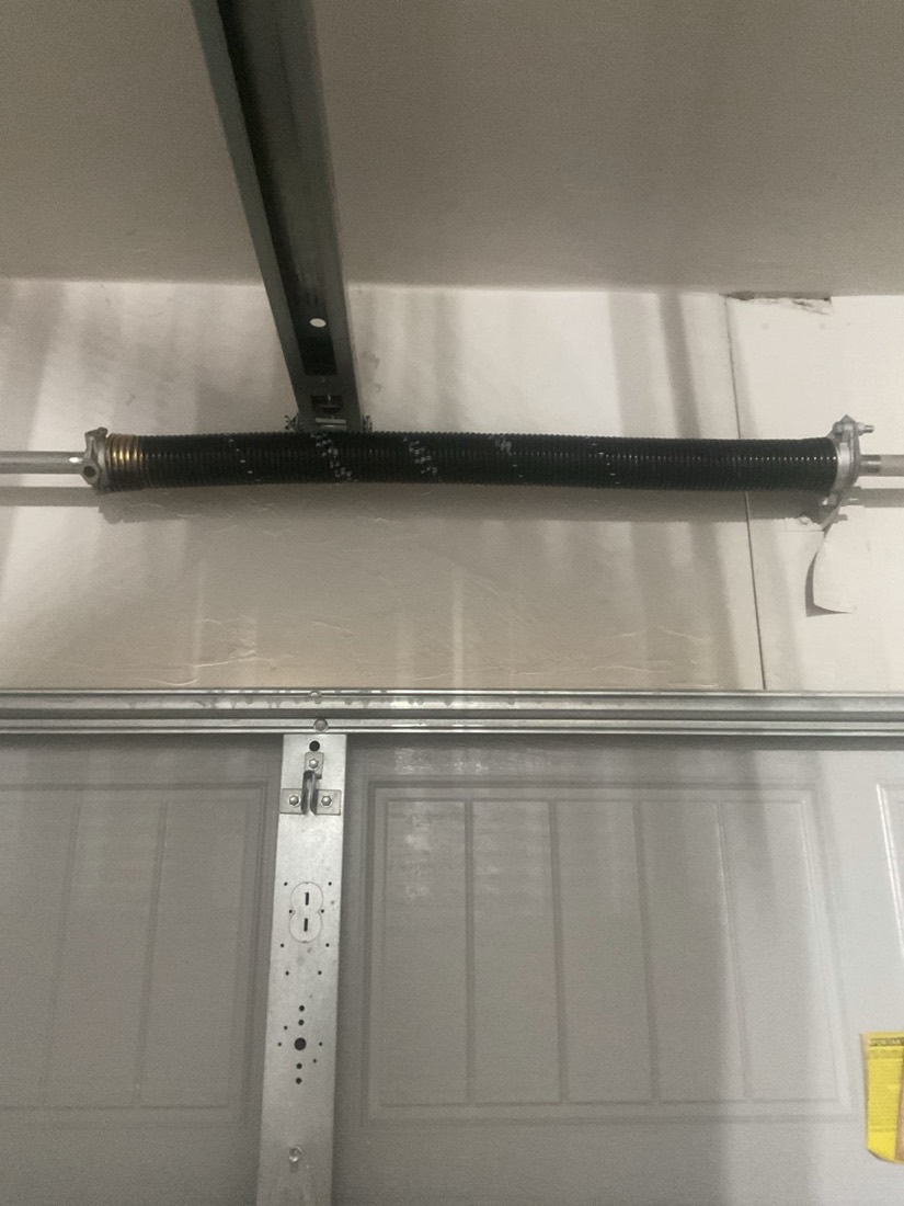 New garage door torsion spring installed above door panel