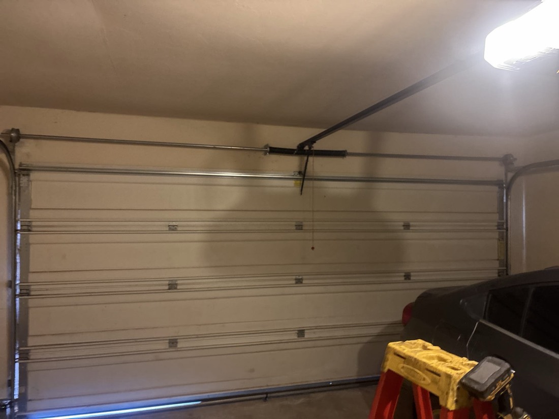 Garage door with new spring hardware and intact panel sections in residential garage.